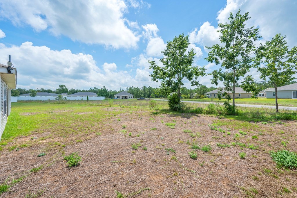 a large yard with trees and a lake in the background