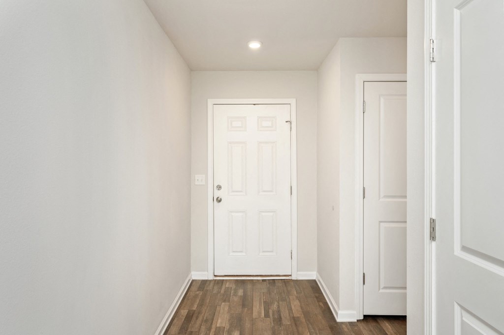 an empty room with a white door and a wooden floor