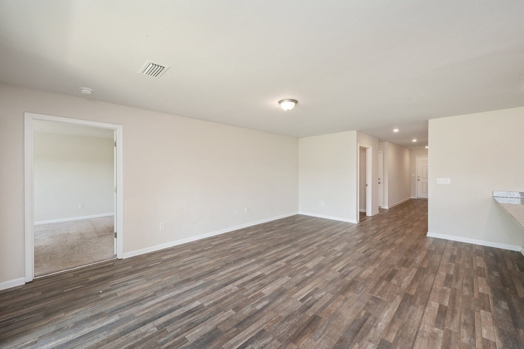 an empty living room with wood floors and white walls