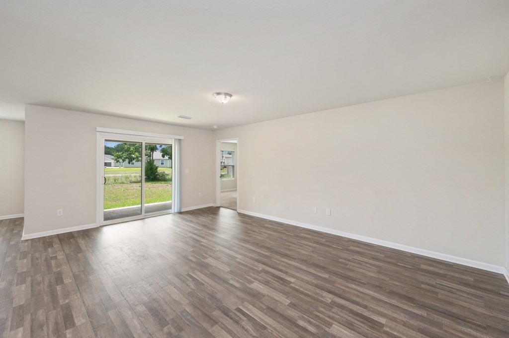the living room of an empty house with wood flooring and a large window