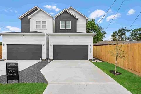 a white house with two garages and a yard with a wooden fence