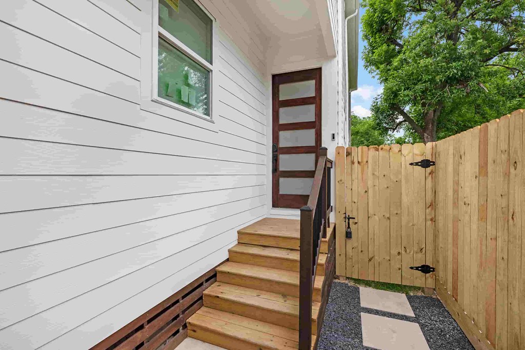 a wooden fence next to a house with stairs next to it