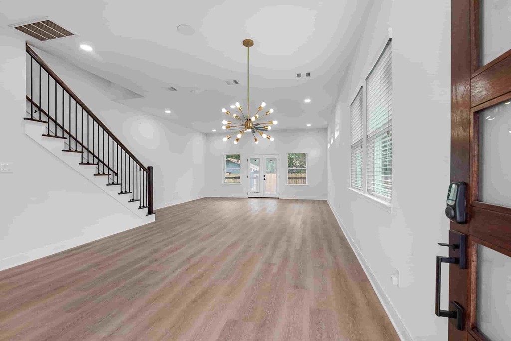 an empty living room with a staircase and a chandelier