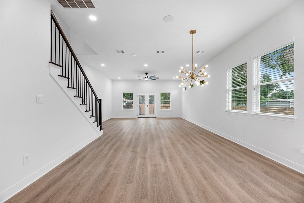 the living room and entryway of a new home with white walls and wood floors