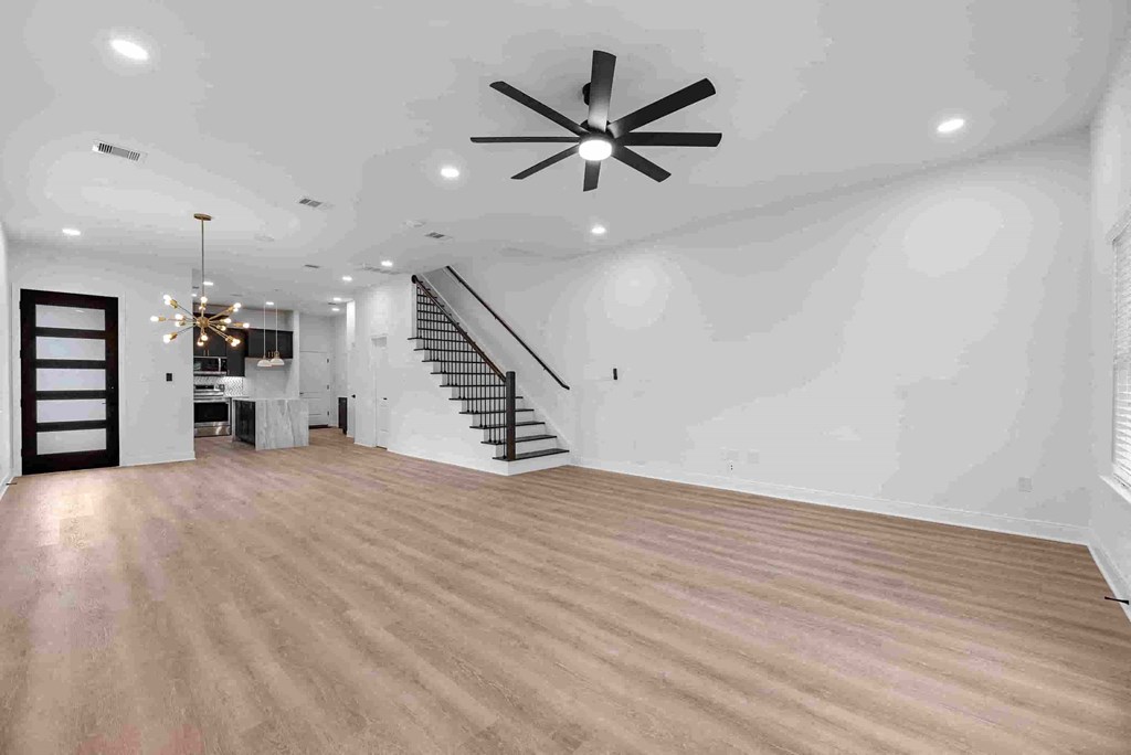 an empty living room with a ceiling fan and a staircase