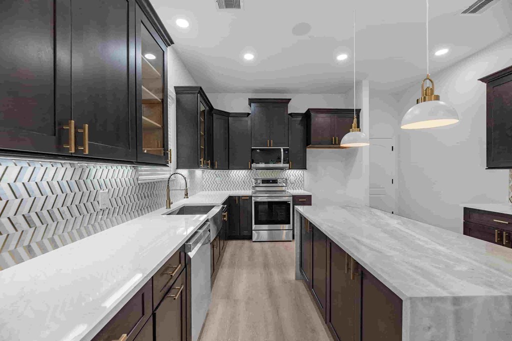 a large kitchen with marble counter tops and black cabinets