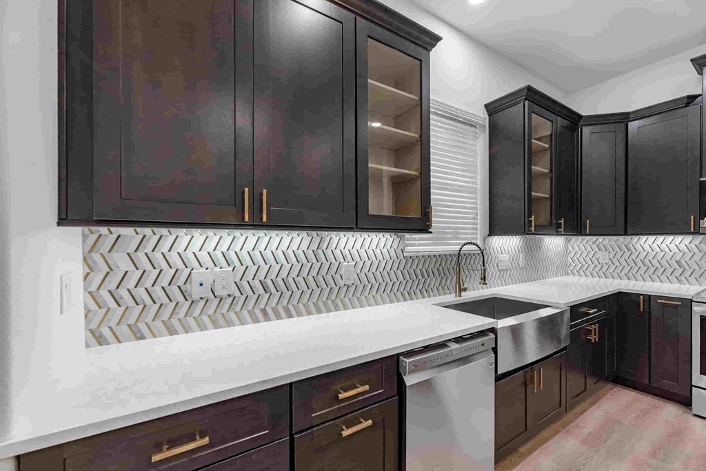 a kitchen with black cabinets and white counter tops and a sink