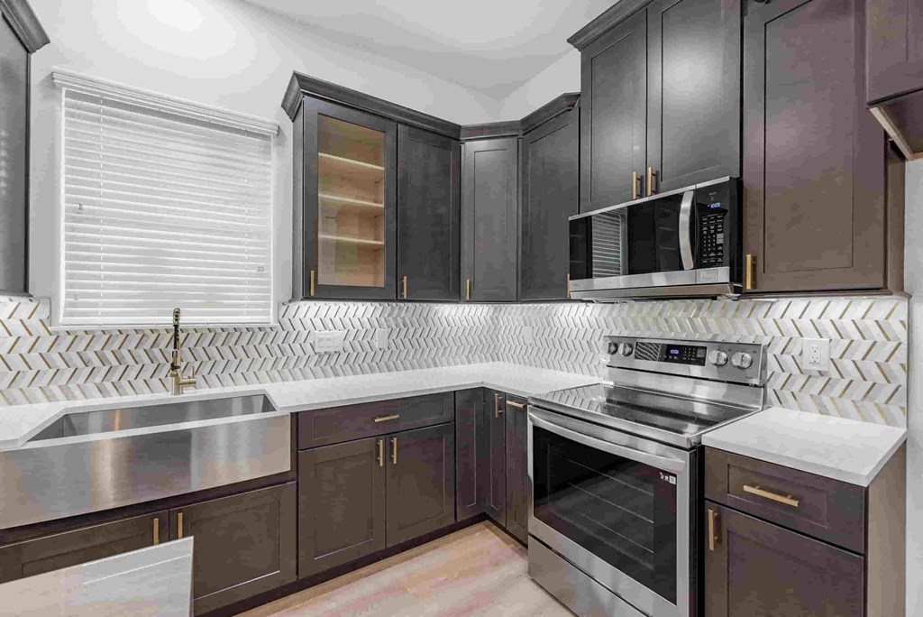 a kitchen with black cabinets and stainless steel appliances