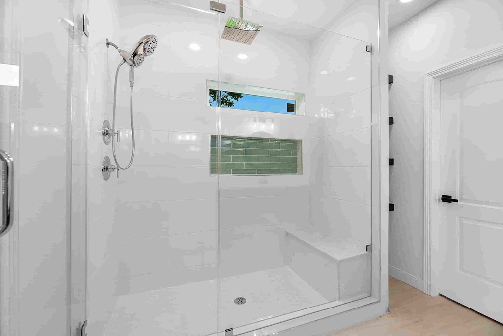a white bathroom with a shower and a window