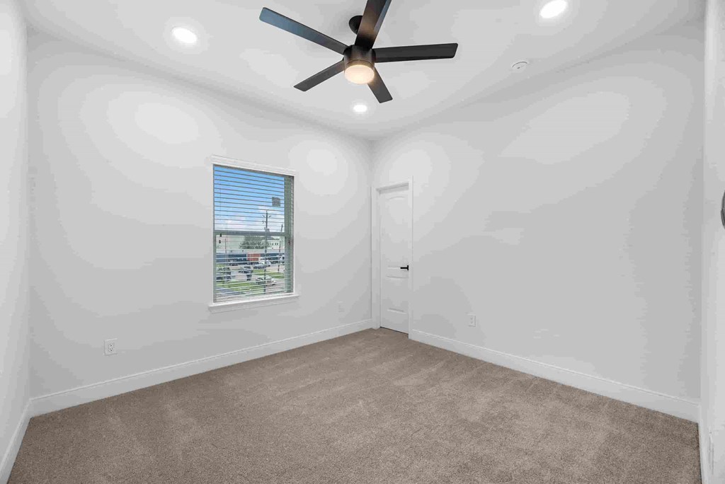an empty living room with a ceiling fan and a door