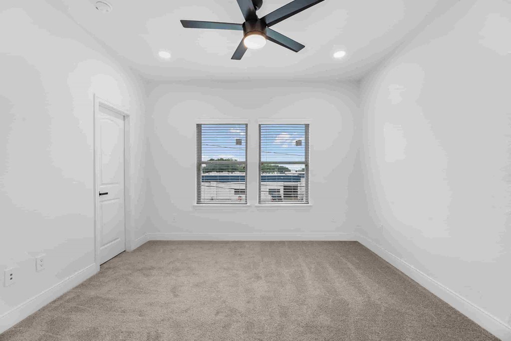 an empty living room with a ceiling fan and a window