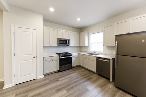 A kitchen with white cabinets and a brown refrigerator.
