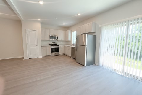 A kitchen with a refrigerator, microwave, and oven.