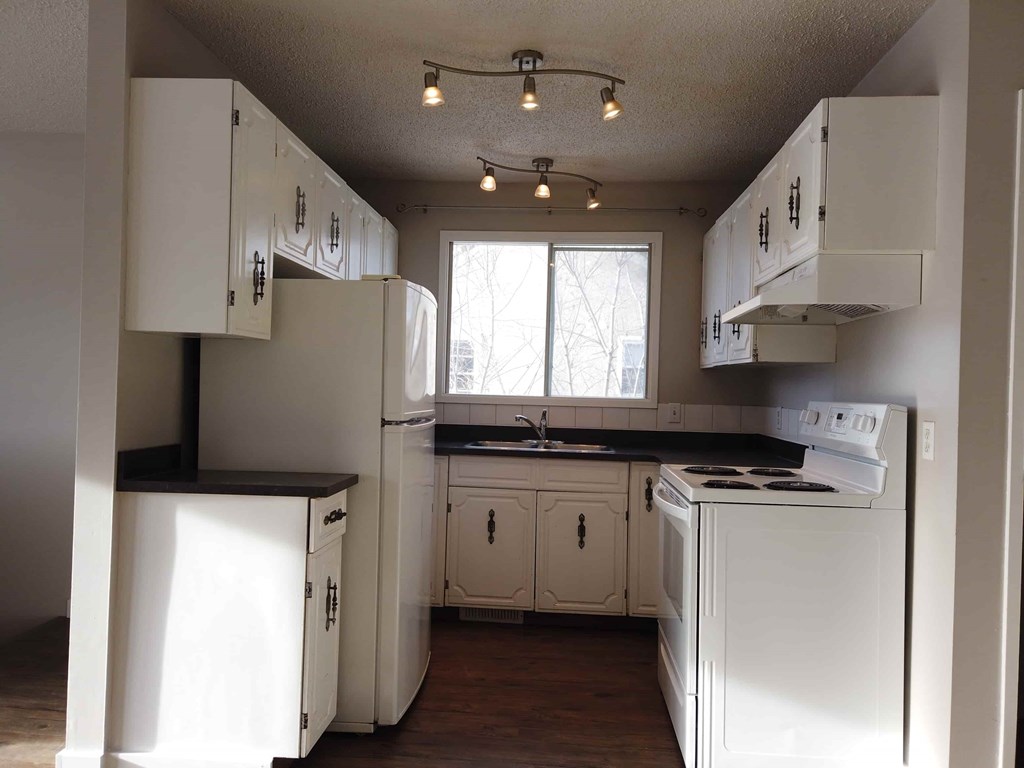 an empty kitchen with white appliances and white cabinets