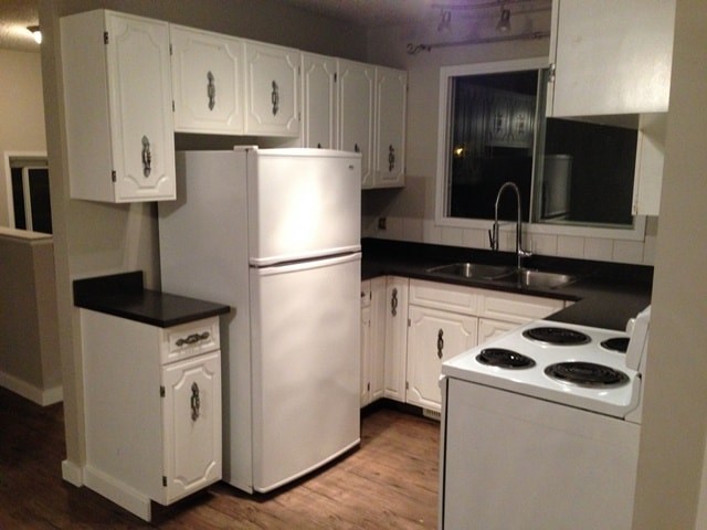 an empty kitchen with white appliances and white cabinets