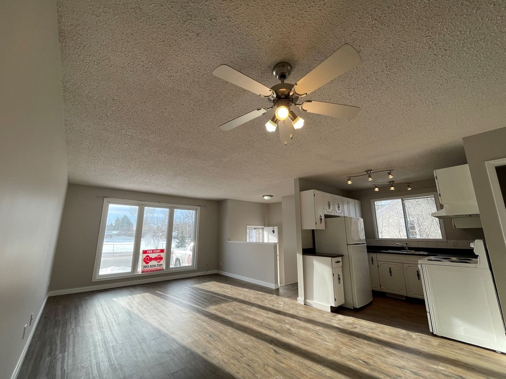 an empty living room and kitchen with a ceiling fan