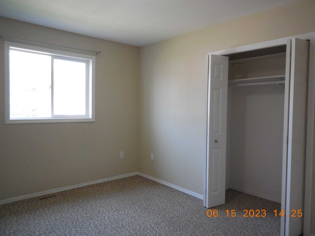 an empty room with a closet and a window