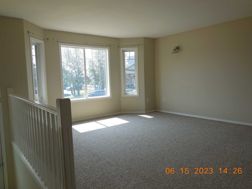 the living room of a new home with white carpet and windows