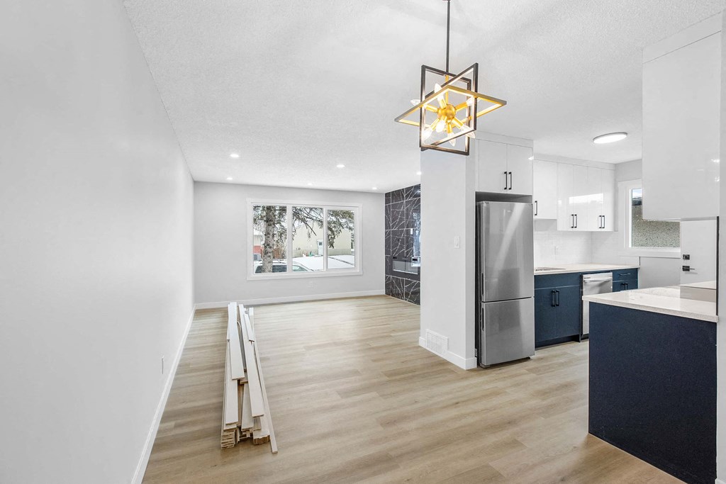 an open kitchen and living room with a counter top refrigerator