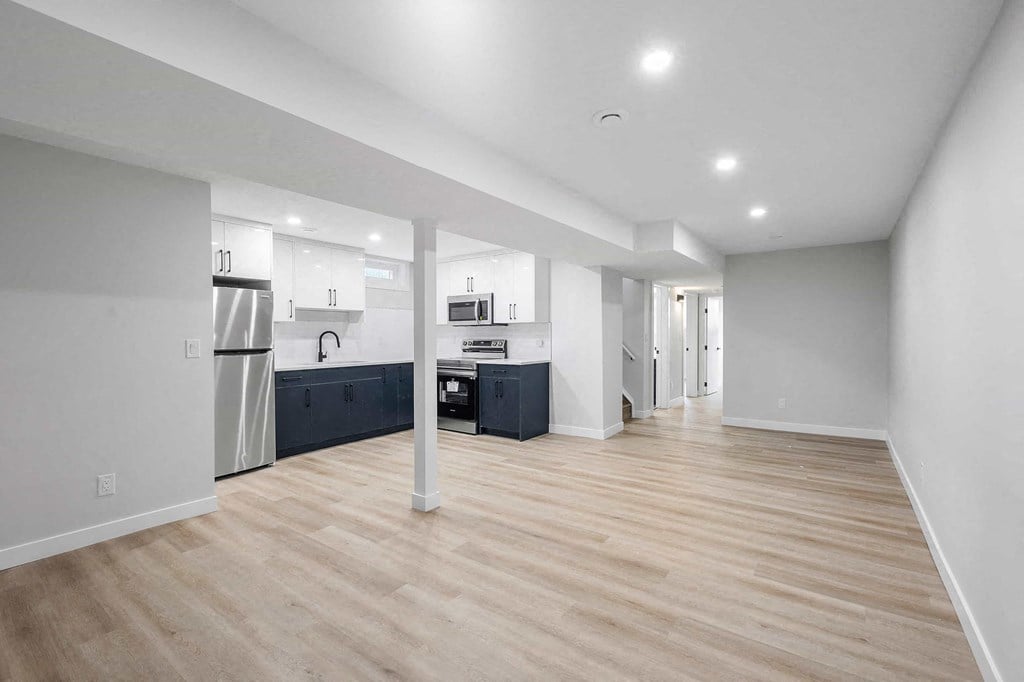 a renovated living room and kitchen with white walls and wood floors