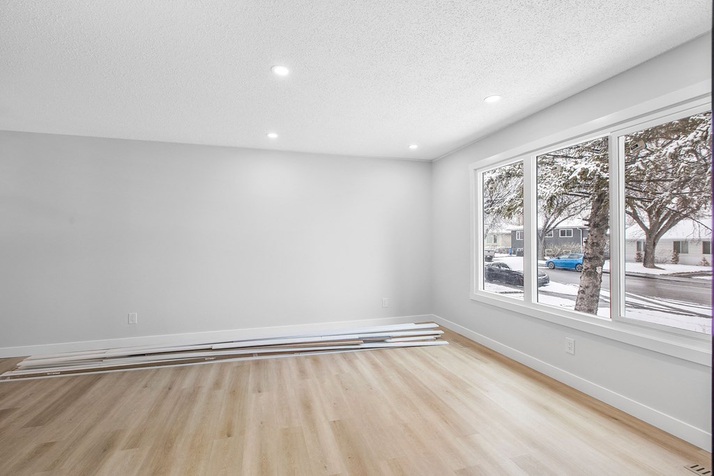 an empty living room with a large window and wooden floors