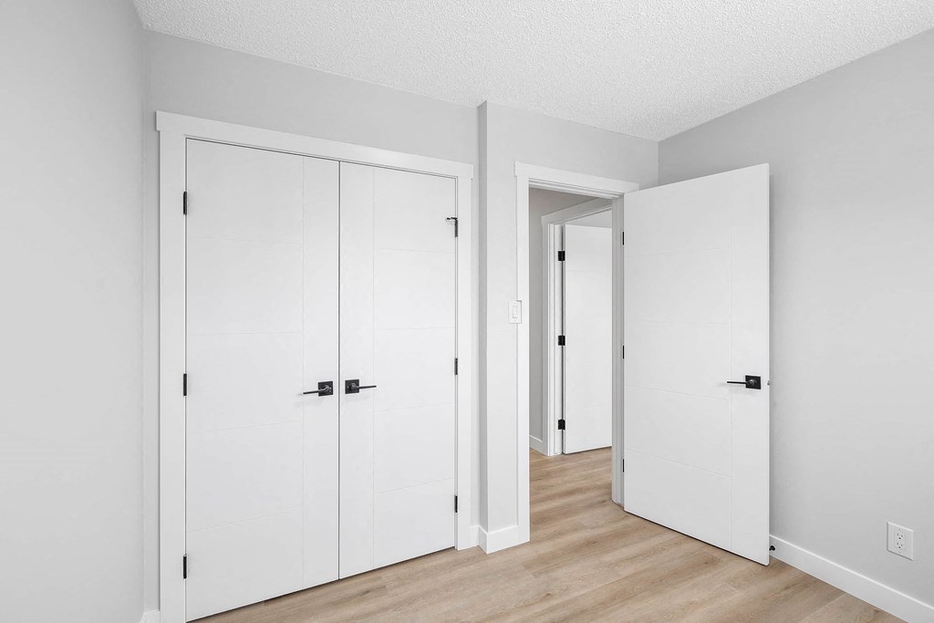 an empty room with white closets and a wood floor