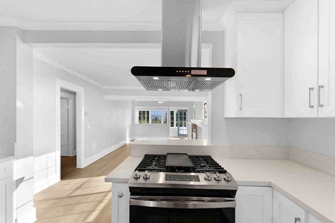 A modern kitchen with a stove top oven and white cabinets.