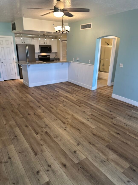 an empty living room and kitchen with wood floors