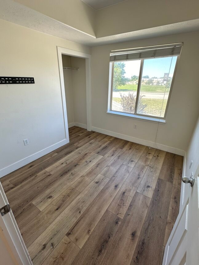 an empty room with a window and wooden floors