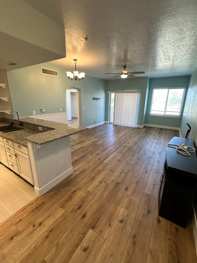an empty living room and kitchen with wood floors