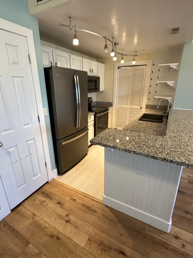 a kitchen with a granite counter top and a stainless steel refrigerator
