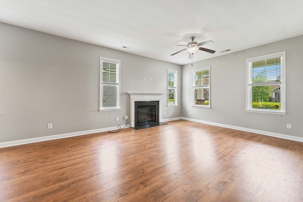an empty living room with wood floors and a fireplace