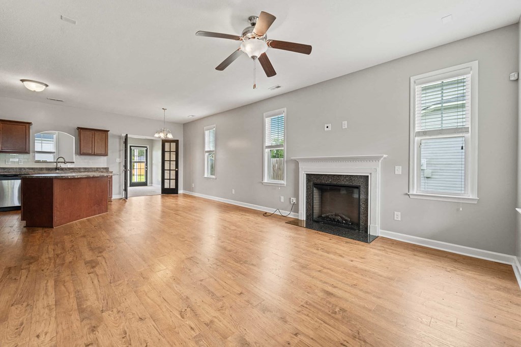 an empty living room with a fireplace and a ceiling fan