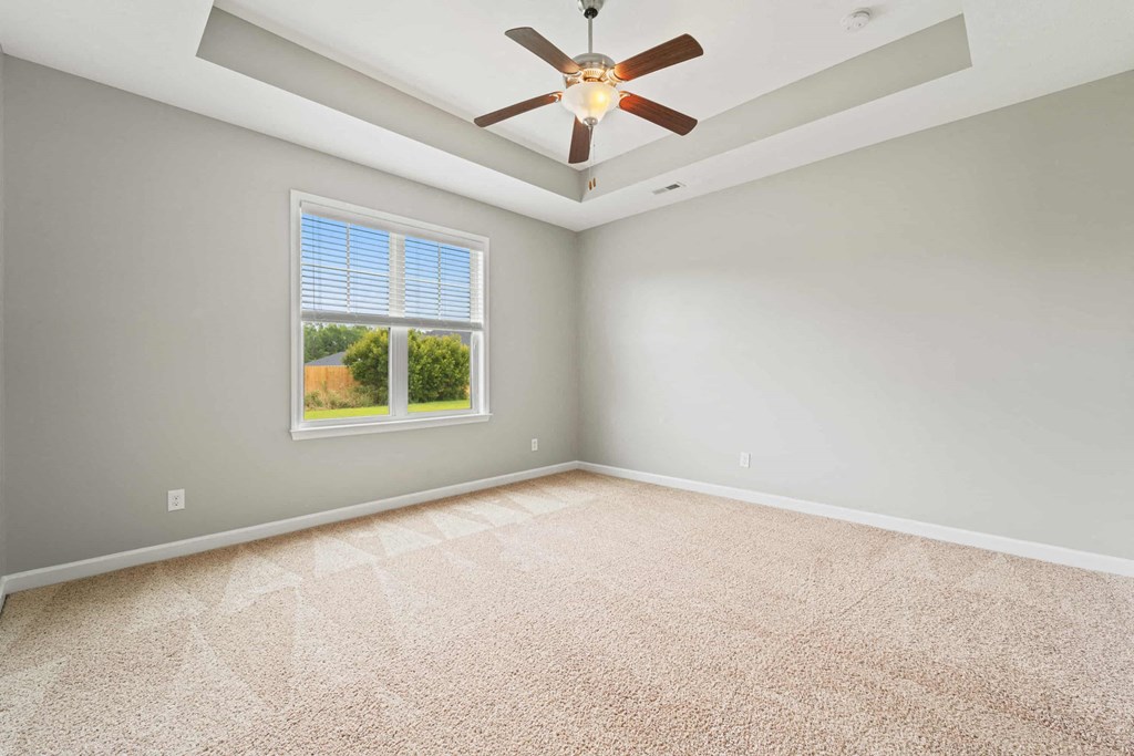 an empty living room with a ceiling fan and a window
