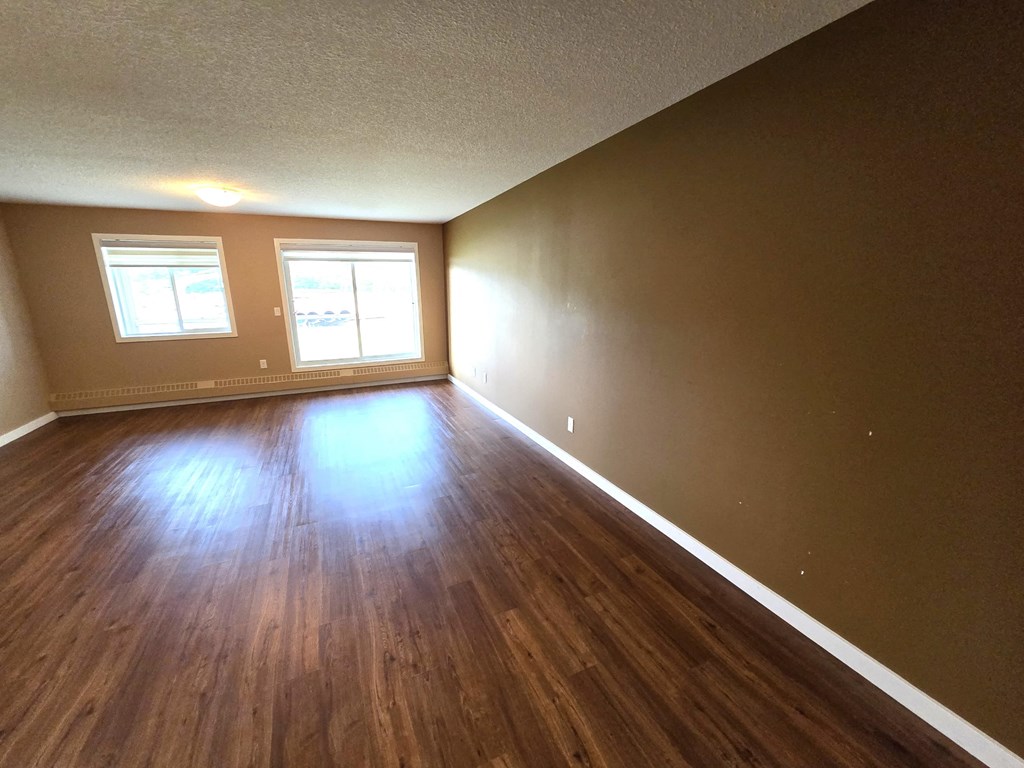 an empty living room with wooden floors and a window