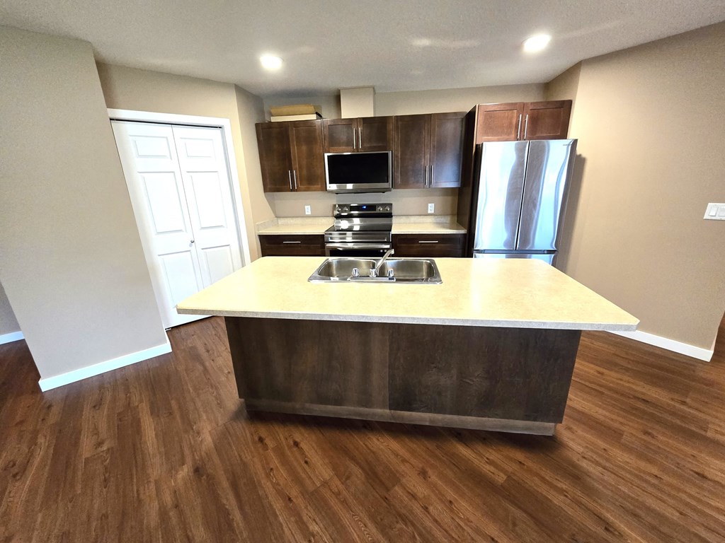 a kitchen with a center island and a stainless steel refrigerator
