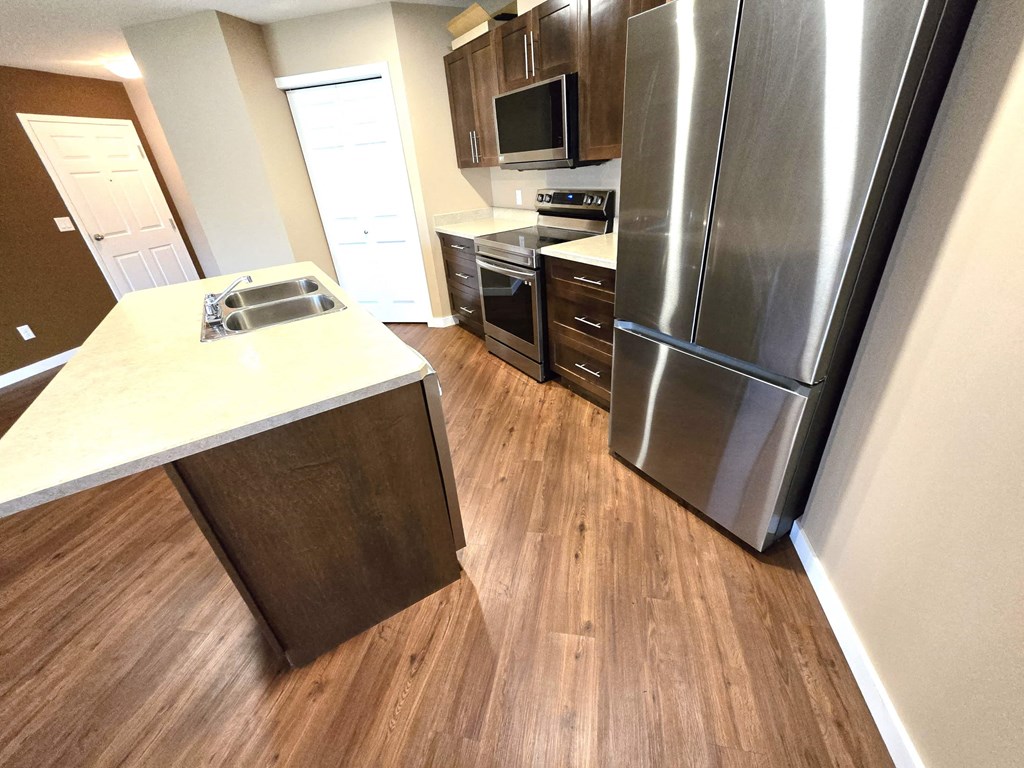 a kitchen with stainless steel appliances and wooden floors