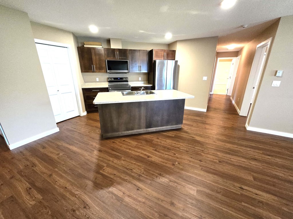a view of a kitchen and living room with wood flooring