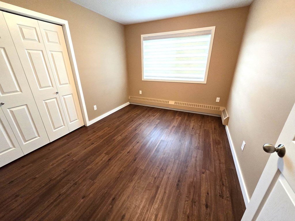 a empty room with wooden floors and a window and a closet