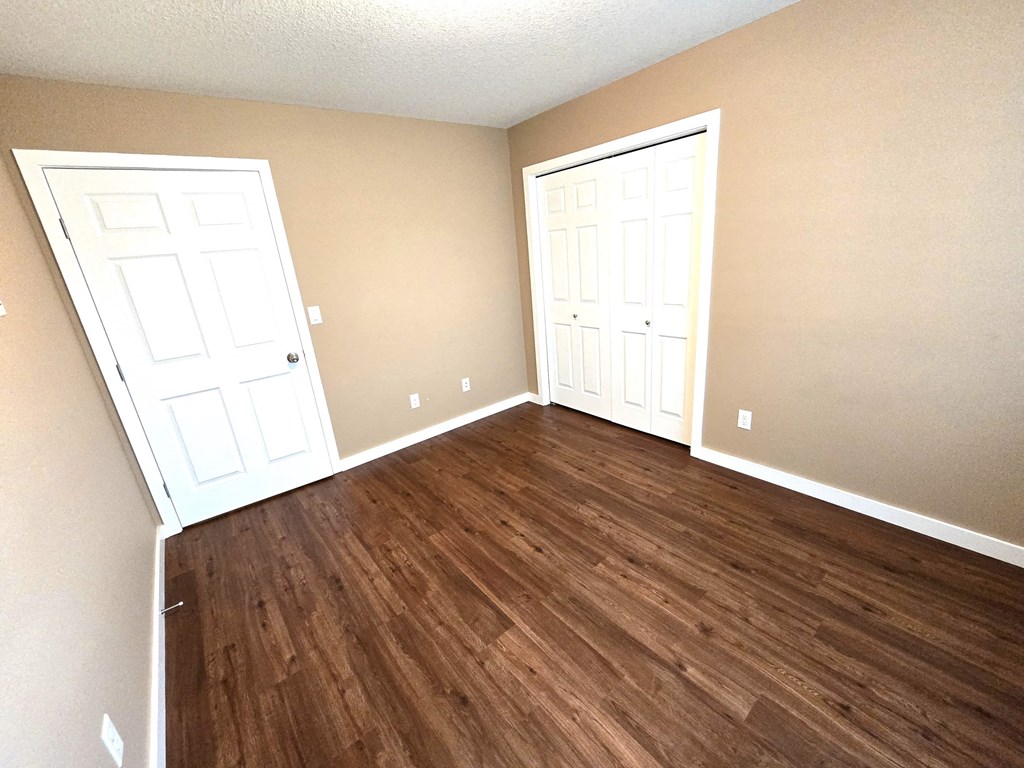 a living room with wood flooring and two doors