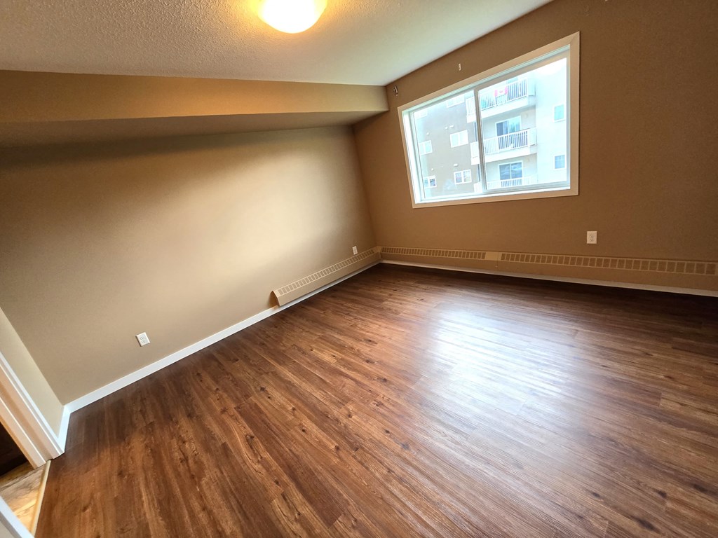 an empty living room with wooden floors and a window