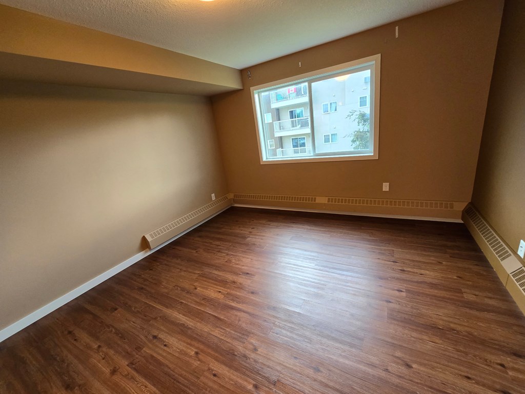 an empty living room with wooden floors and a window