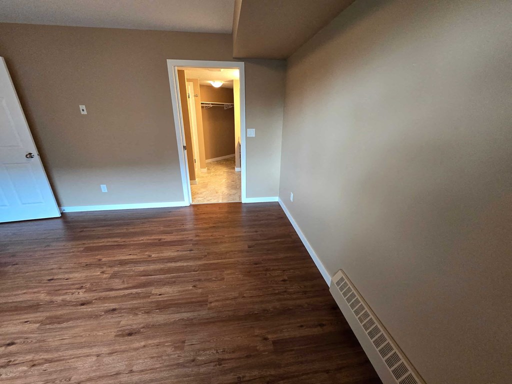 a empty living room with wooden floors and grey walls