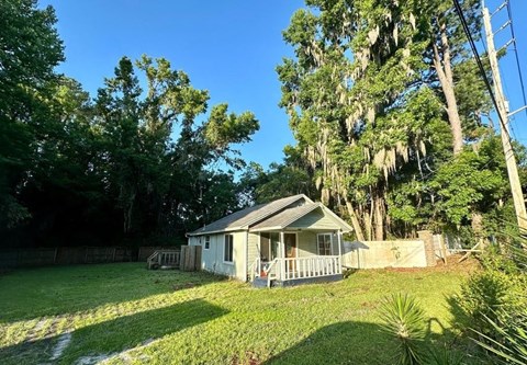 a small white house with a yard and trees