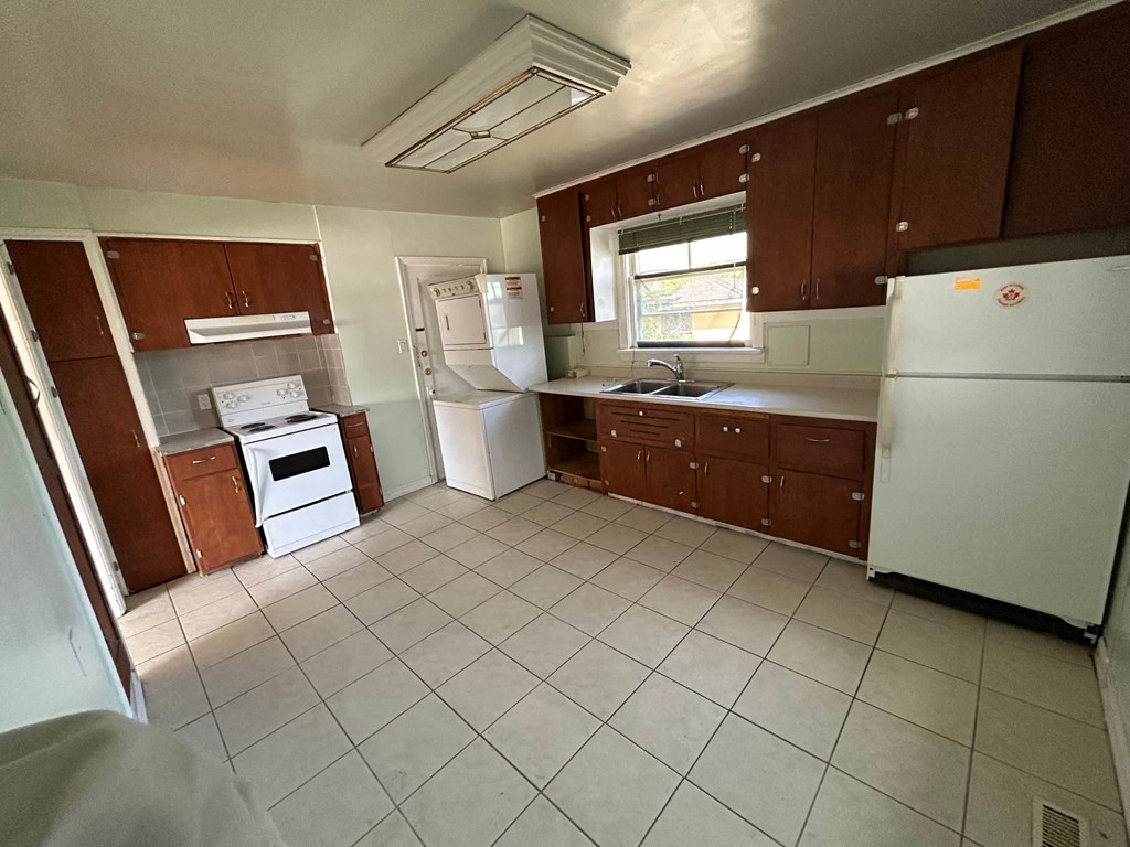an empty kitchen with white appliances and wooden cabinets