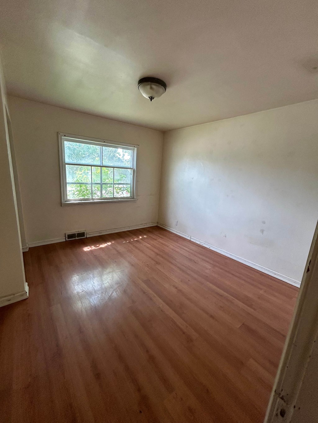 an empty room with wooden floors and a window