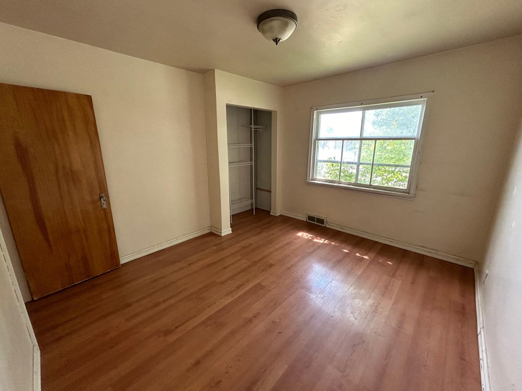 an empty room with wooden floors and a window