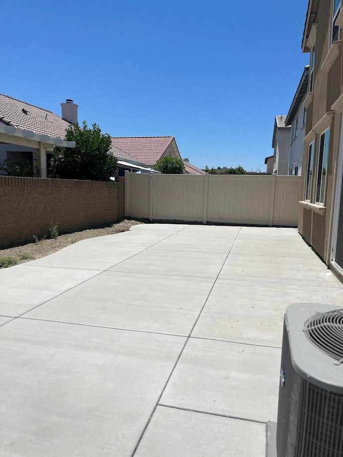 a backyard with a long concrete driveway and a fence