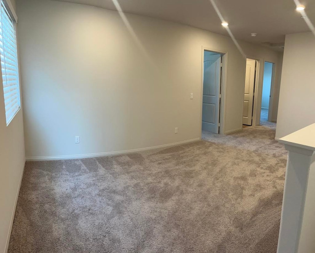 a living room with carpet and a door to a bedroom