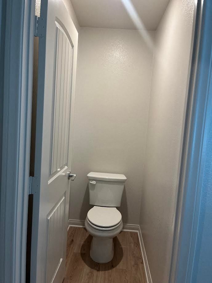 a white toilet in a small bathroom with a door